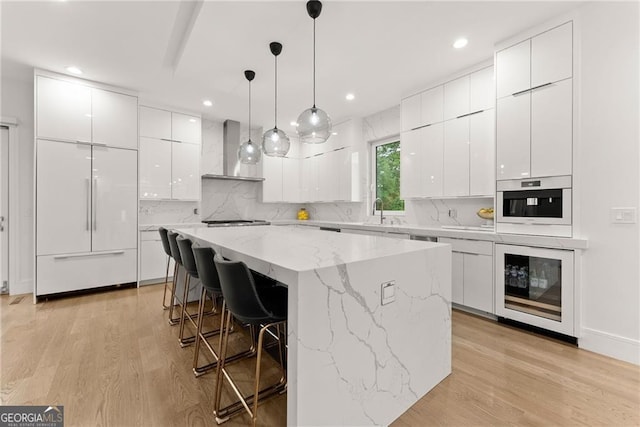 kitchen with light hardwood / wood-style flooring, white cabinets, beverage cooler, and a kitchen island