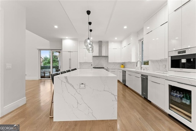 kitchen featuring white cabinets, decorative light fixtures, light hardwood / wood-style floors, and a center island