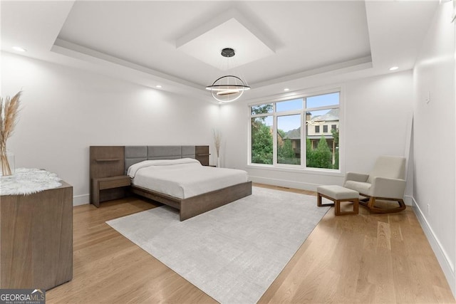 bedroom featuring a tray ceiling and light hardwood / wood-style floors