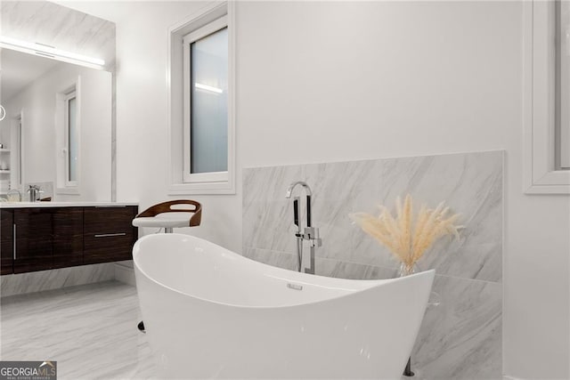 bathroom featuring a tub to relax in, tile walls, and vanity