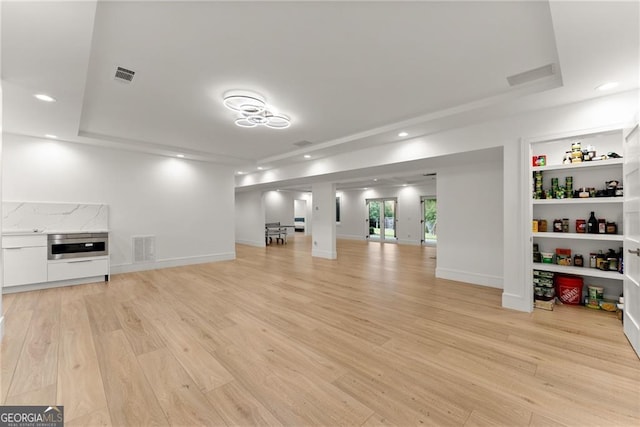 unfurnished living room with a tray ceiling and light hardwood / wood-style floors