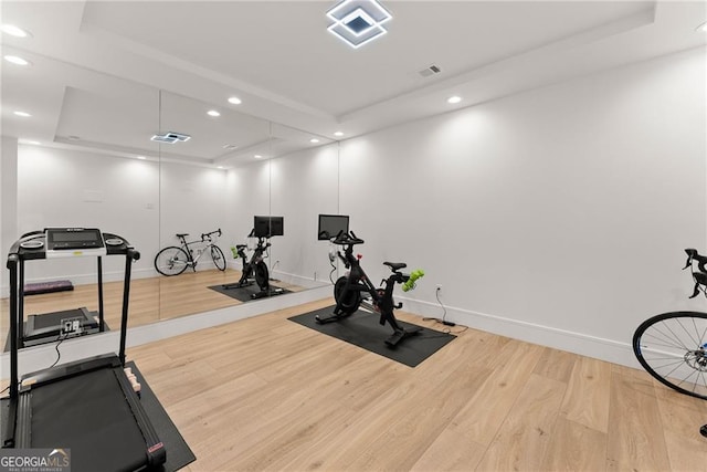 exercise room with wood-type flooring and a raised ceiling