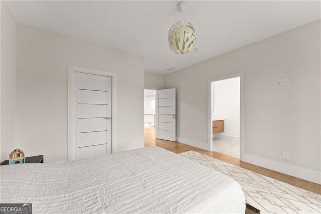 bedroom featuring a closet, ensuite bath, and light hardwood / wood-style floors