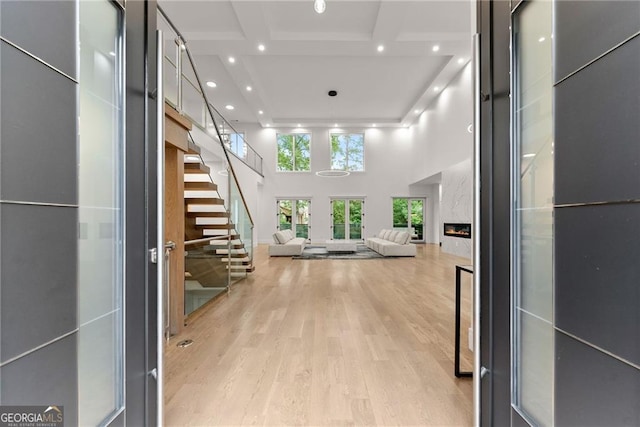 hallway with light hardwood / wood-style flooring and a towering ceiling