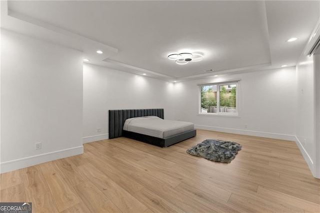 unfurnished bedroom featuring light hardwood / wood-style flooring and a raised ceiling