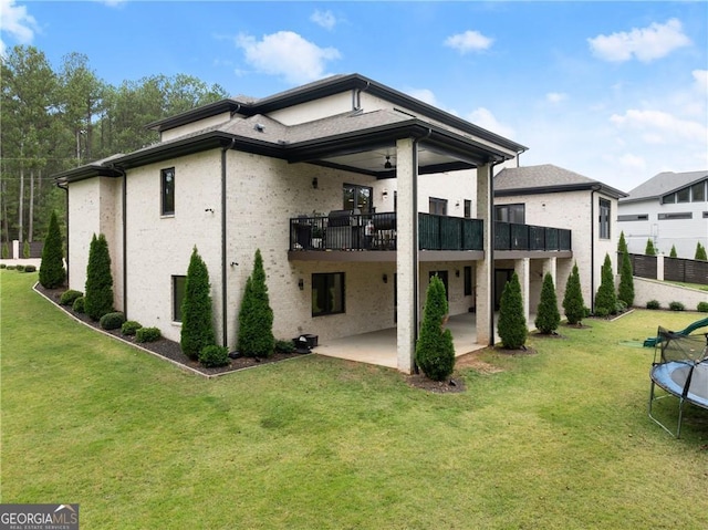 rear view of house with a lawn, a trampoline, and a patio area