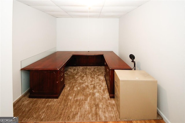 home office with light hardwood / wood-style floors and a paneled ceiling