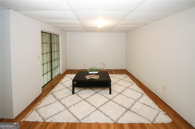 living area with a paneled ceiling and hardwood / wood-style flooring