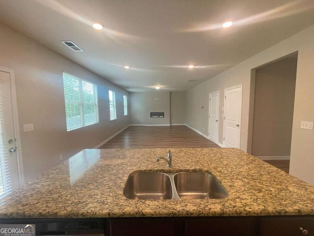 kitchen featuring light stone counters, sink, a kitchen island with sink, black dishwasher, and dark hardwood / wood-style flooring