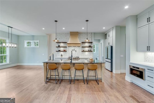 kitchen featuring decorative light fixtures, fridge, custom range hood, and a large island