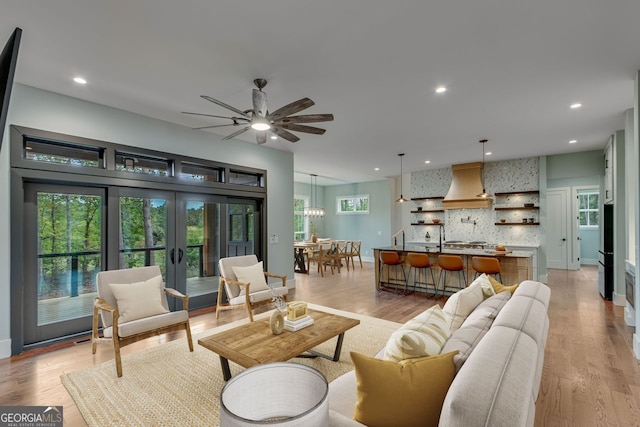 living room with light hardwood / wood-style floors, french doors, and ceiling fan