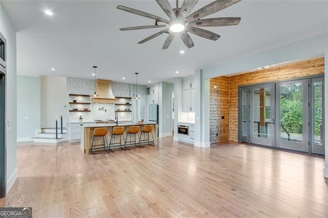 living room with light wood-type flooring, french doors, and ceiling fan