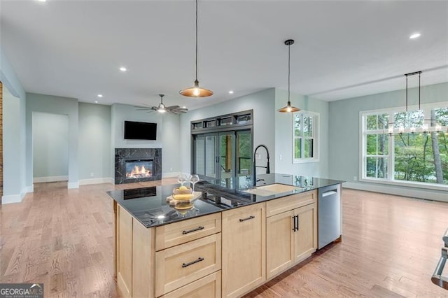 kitchen featuring a fireplace, decorative light fixtures, light hardwood / wood-style floors, sink, and stainless steel dishwasher