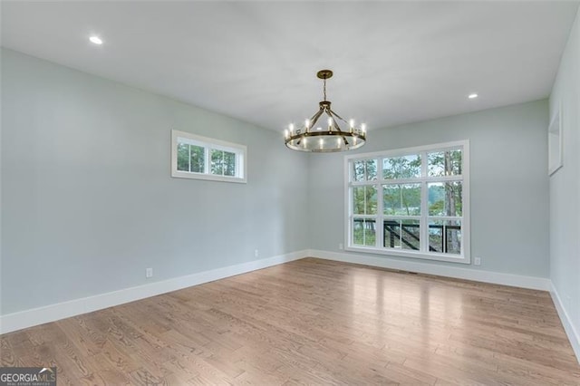 spare room with light wood-type flooring and a chandelier