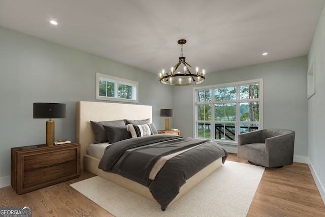 bedroom with light wood-type flooring, a chandelier, and multiple windows