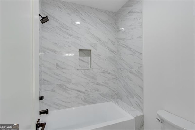 bathroom with toilet and tiled shower / bath