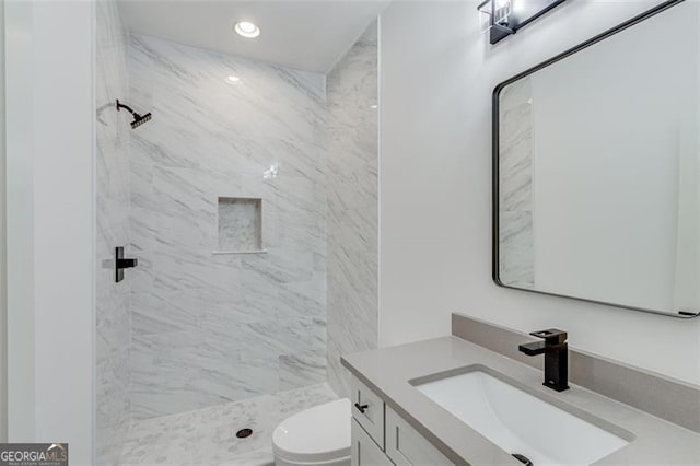 bathroom featuring toilet, vanity, and tiled shower