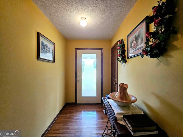 doorway with a textured ceiling and dark wood-type flooring