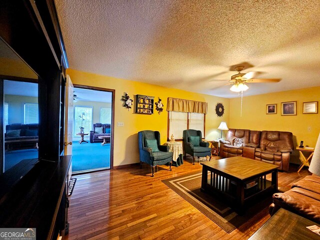 living room featuring ceiling fan, a textured ceiling, and hardwood / wood-style floors