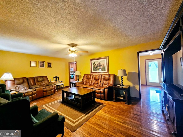 living room with ceiling fan, a textured ceiling, and hardwood / wood-style floors