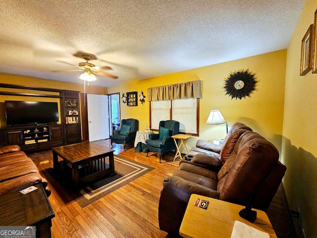 living room featuring ceiling fan, hardwood / wood-style flooring, and a textured ceiling