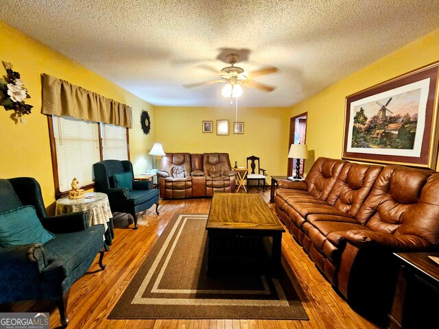 living room featuring wood-type flooring, a textured ceiling, and ceiling fan