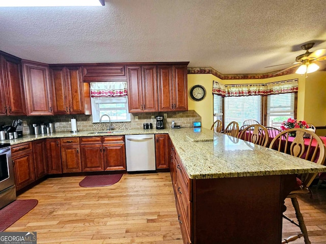 kitchen featuring dishwasher, light wood-type flooring, sink, and a kitchen bar