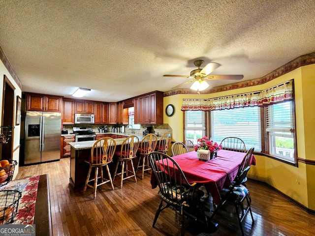 dining space with wood-type flooring, a textured ceiling, sink, and ceiling fan