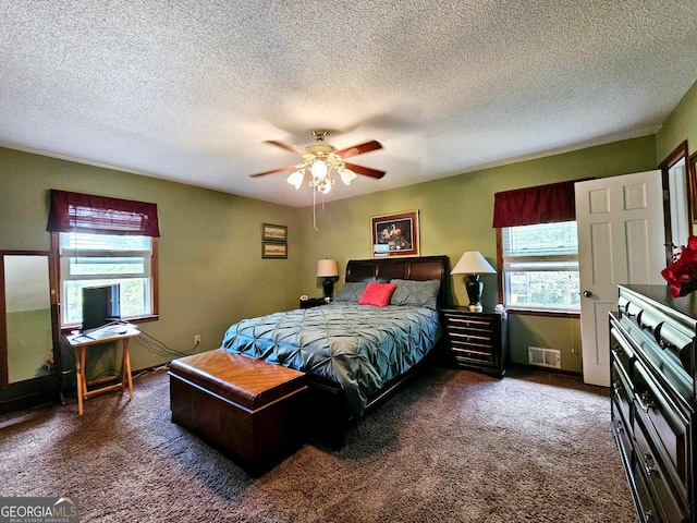 carpeted bedroom with ceiling fan and a textured ceiling