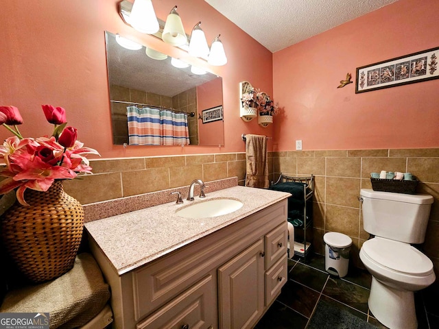 bathroom with tile walls, tile patterned flooring, a textured ceiling, vanity, and toilet