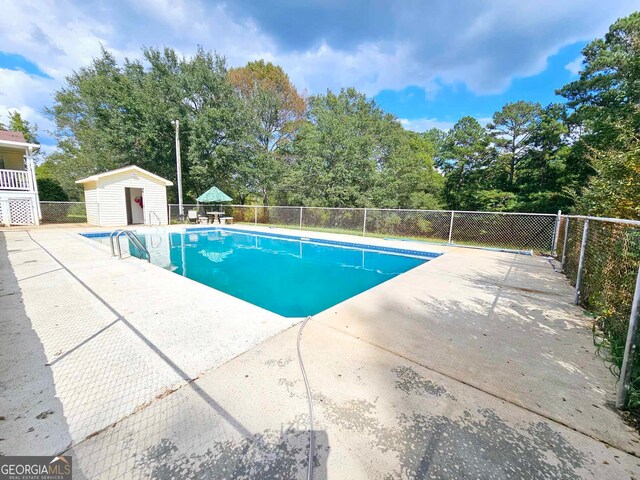 view of pool with a storage shed and a patio area