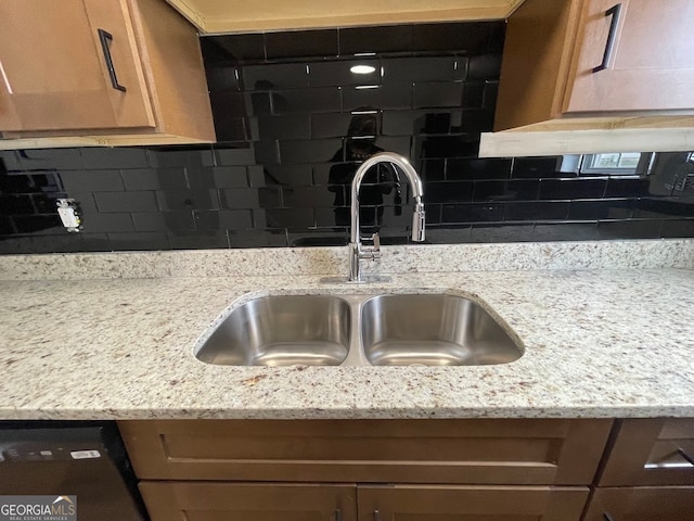 room details with light stone counters, dishwasher, sink, and tasteful backsplash