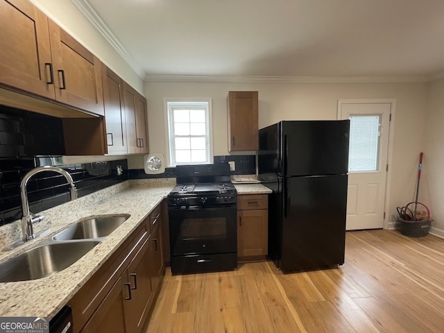 kitchen featuring light stone counters, light hardwood / wood-style floors, sink, black appliances, and ornamental molding