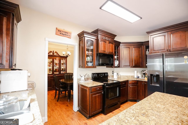 kitchen with black appliances, light hardwood / wood-style floors, and light stone counters