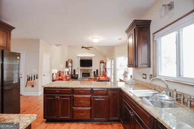 kitchen with ceiling fan, sink, stainless steel refrigerator, light wood-type flooring, and vaulted ceiling