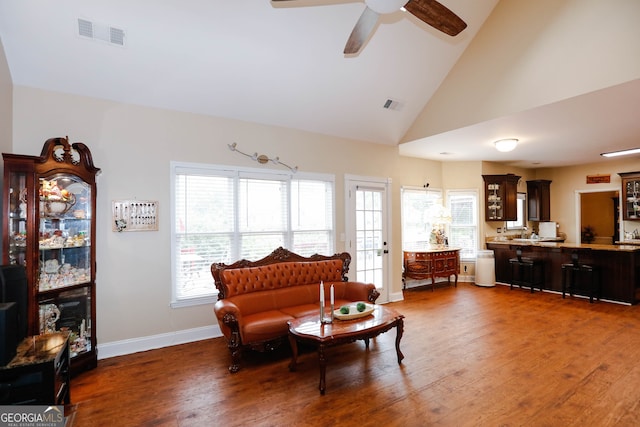 living area with high vaulted ceiling, ceiling fan, plenty of natural light, and dark hardwood / wood-style flooring