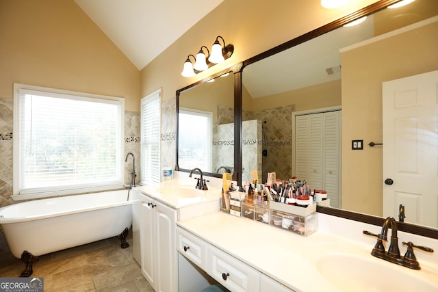 bathroom with a tub to relax in, vanity, and vaulted ceiling