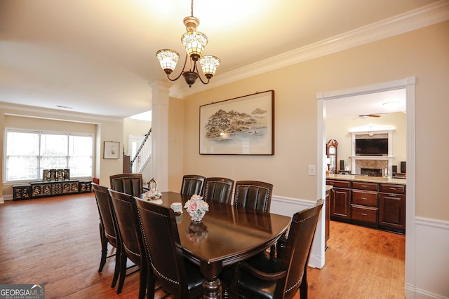 dining space featuring light hardwood / wood-style flooring, a chandelier, decorative columns, and crown molding