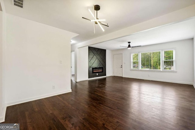 unfurnished living room featuring ceiling fan with notable chandelier, a large fireplace, and dark hardwood / wood-style flooring