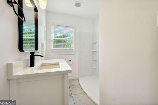 bathroom featuring vanity, a shower, tile patterned flooring, and toilet