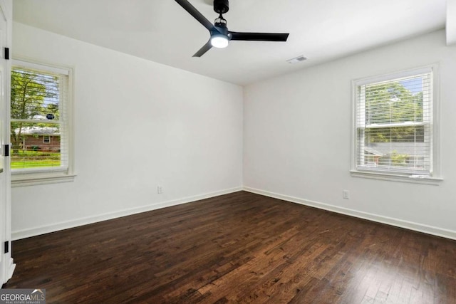 empty room featuring a healthy amount of sunlight, dark hardwood / wood-style flooring, and ceiling fan