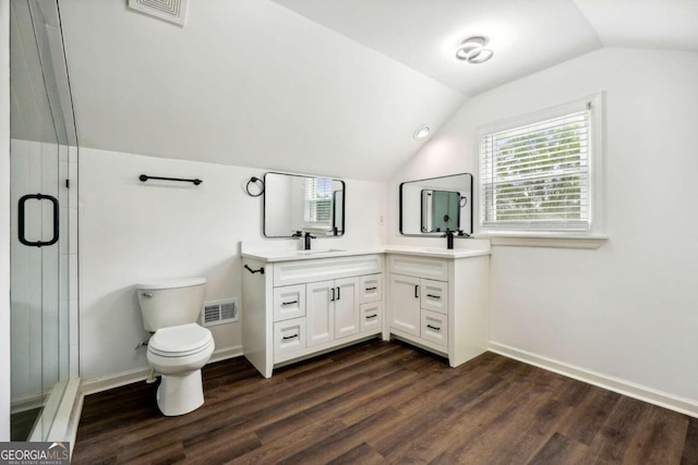 bathroom featuring hardwood / wood-style flooring, vaulted ceiling, a shower with shower door, vanity, and toilet