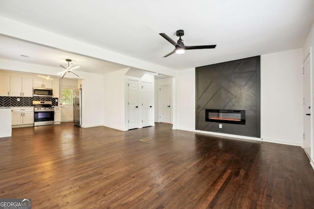 unfurnished living room with ceiling fan, a tile fireplace, and dark hardwood / wood-style floors