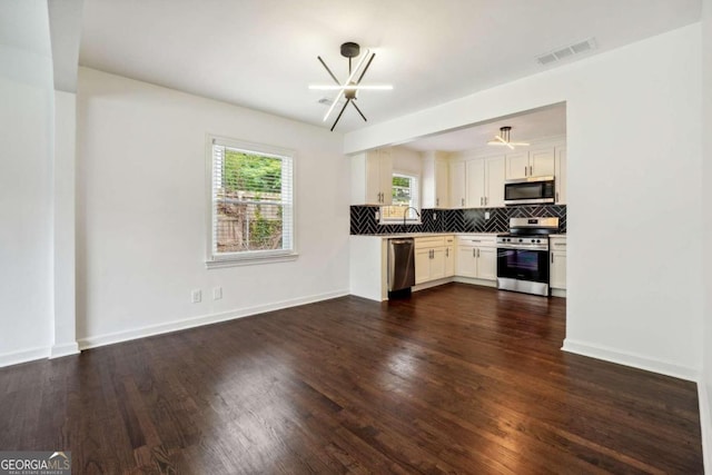 kitchen featuring a notable chandelier, white cabinets, appliances with stainless steel finishes, and dark wood-type flooring