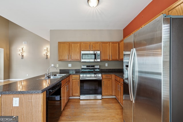 kitchen featuring appliances with stainless steel finishes, sink, kitchen peninsula, and light hardwood / wood-style flooring