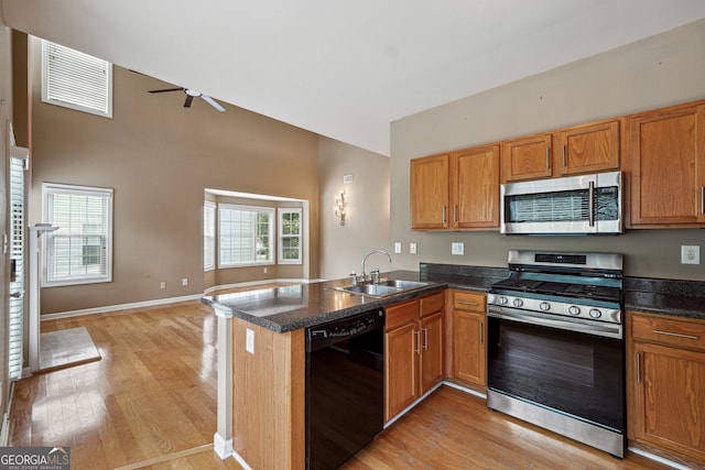 kitchen with ceiling fan, sink, kitchen peninsula, stainless steel appliances, and light wood-type flooring