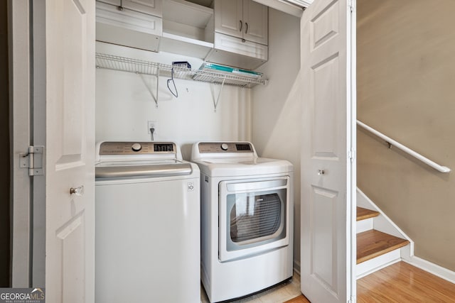 laundry area featuring cabinets, light hardwood / wood-style floors, and independent washer and dryer