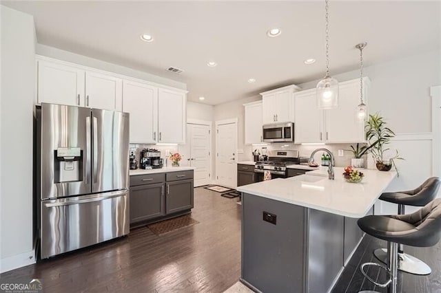 kitchen with pendant lighting, white cabinets, kitchen peninsula, and appliances with stainless steel finishes