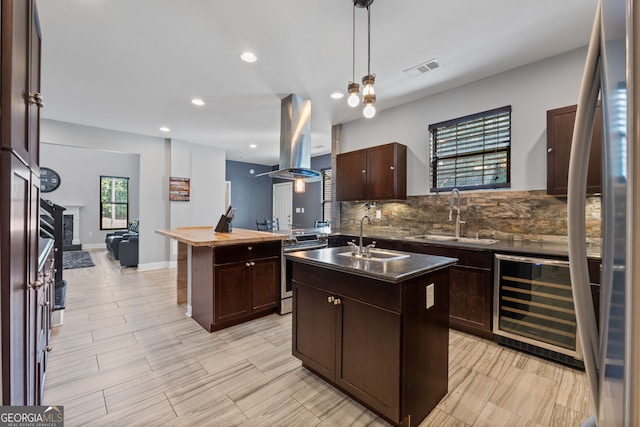 kitchen with an island with sink, tasteful backsplash, a sink, wine cooler, and island range hood