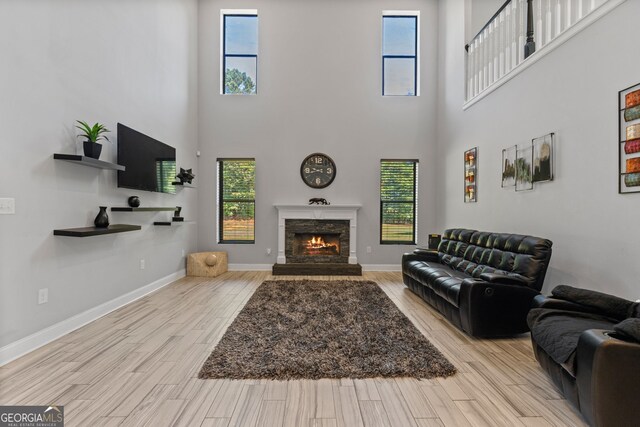 living room with a towering ceiling, light hardwood / wood-style flooring, and plenty of natural light